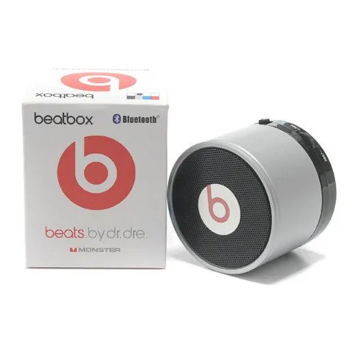 A picture of a Beats Bluetooth speaker that is round but flat on the top and bottom, it has the Beats "b" on the top.